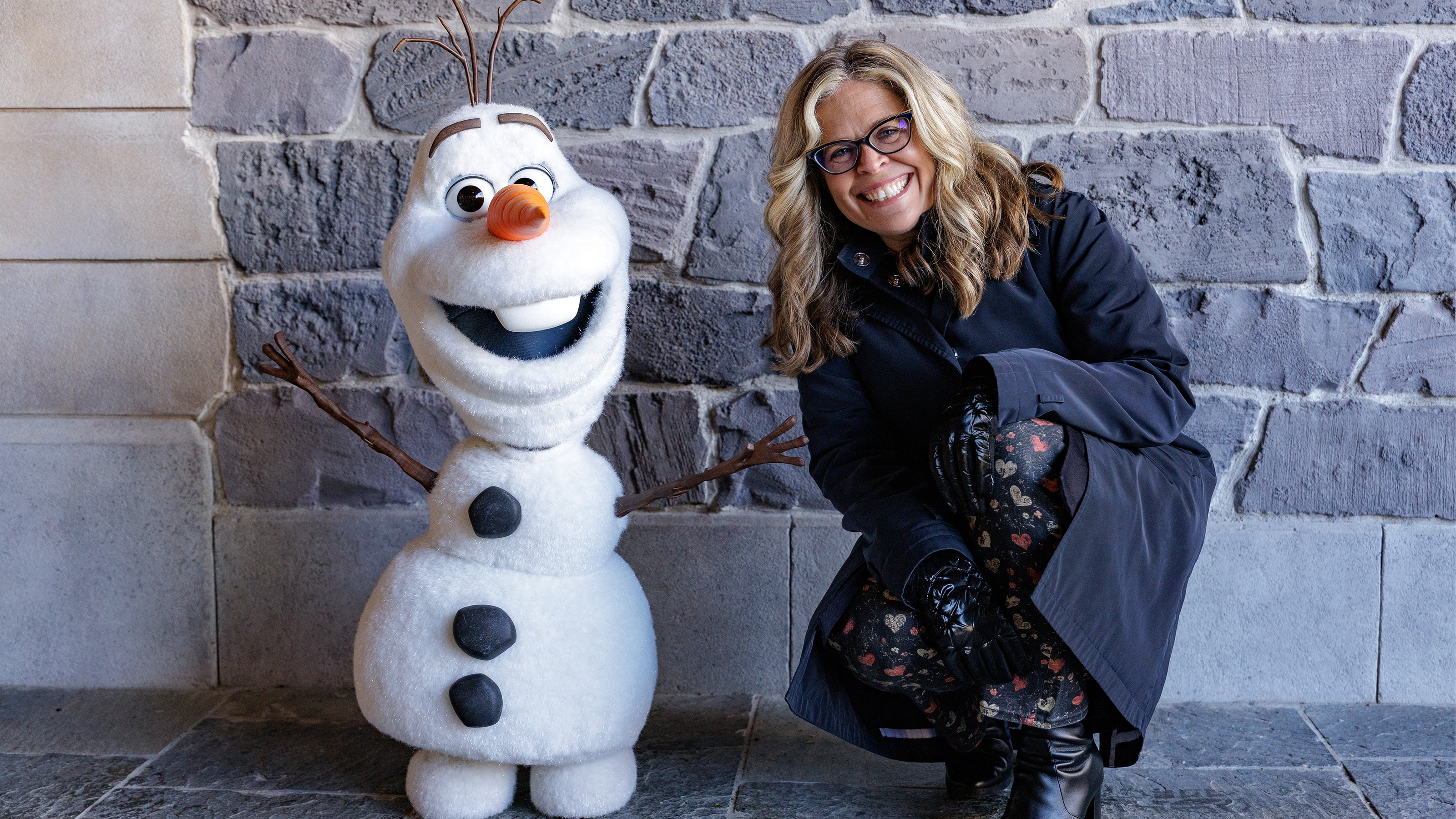 Jennifer Lee poses with Olaf while discussing Frozen's lasting impact on Disney Parks in Disney Worldbuilders.