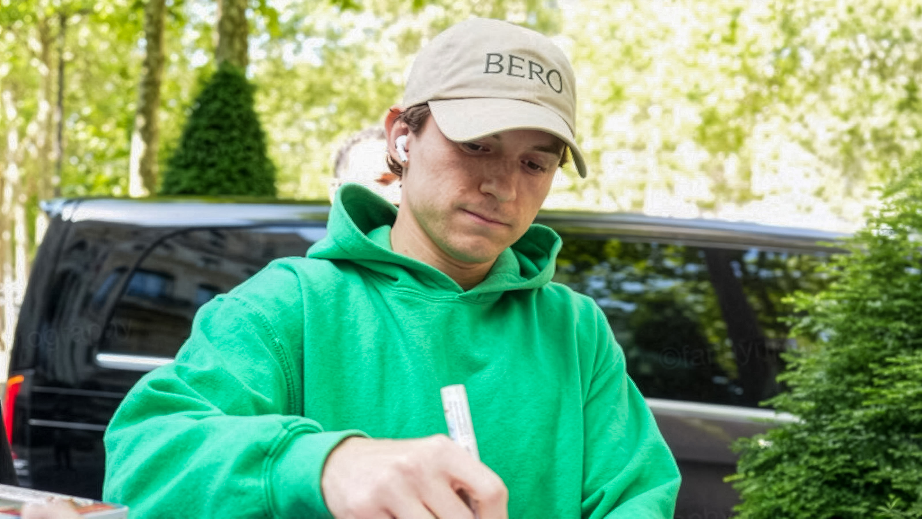 Tom Holland signs Spider-Man collectibles for fans during the Spider-Man: Brand New Day event in Paris.